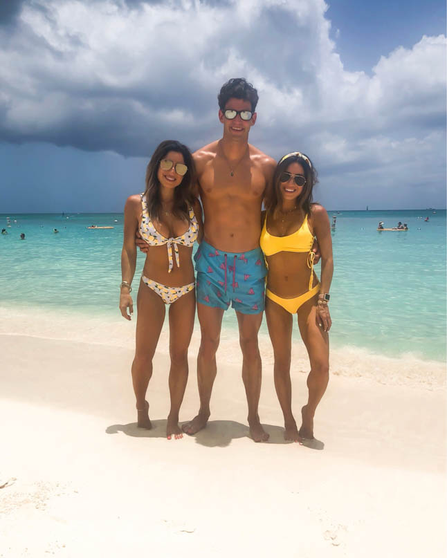 identical twins wearing yellow bikini and lemon print bikini on seven mile beach at the ritz carlton grand cayman