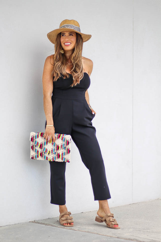 fashion blogger wearing black jumpsuit for petites with a rainbow knitted clutch from sole society, a floppy hat, and some bow neutral slide sandals | adoubledose.com