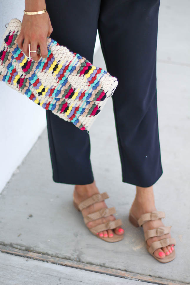 fashion blogger wearing black jumpsuit for petites with a rainbow knitted clutch from sole society, a floppy hat, and some bow neutral slide sandals | adoubledose.com