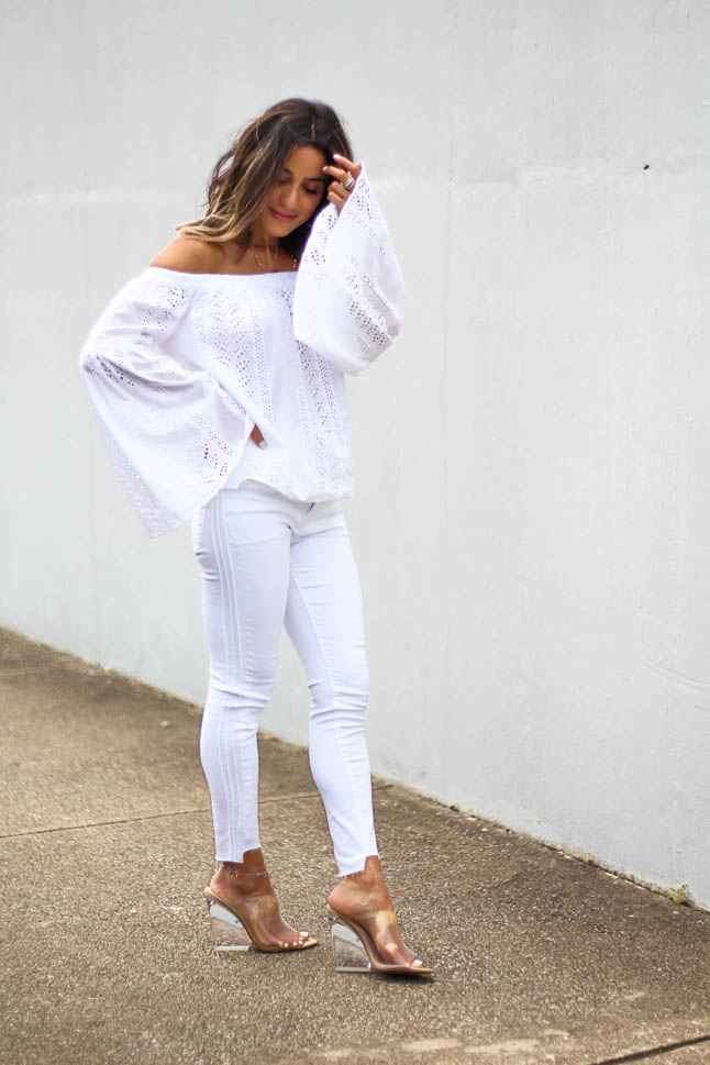 lifestyle and fashion blogger alexis belbel shares an all white look from express: a white off shoulder eyelet top with bell sleeves and some skinny white ankle jeans with clear wedge sandals