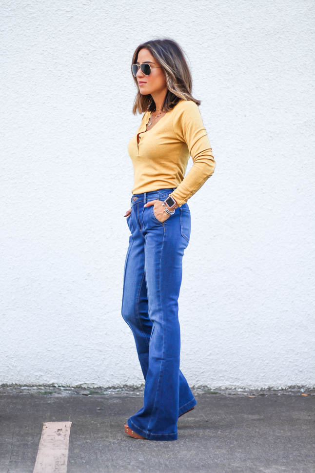 lifestlye and fashion blogger alexis belbel wearing a head to toe look from walmart we dress america. Wearing a faux leather moto jacket, yellow henley top with buttons, and high rise flare jeans for fall
