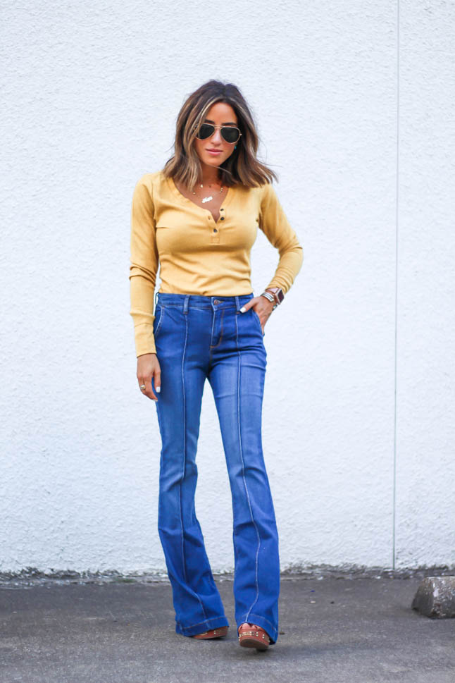 lifestlye and fashion blogger alexis belbel wearing a head to toe look from walmart we dress america. Wearing a faux leather moto jacket, yellow henley top with buttons, and high rise flare jeans for fall