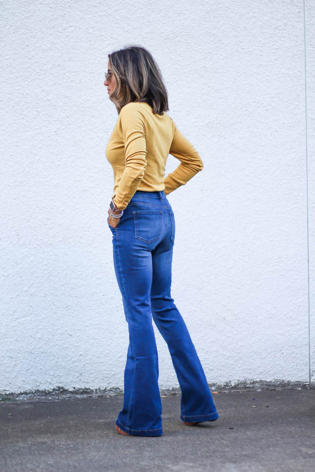 lifestlye and fashion blogger alexis belbel wearing a head to toe look from walmart we dress america. Wearing a faux leather moto jacket, yellow henley top with buttons, and high rise flare jeans for fall