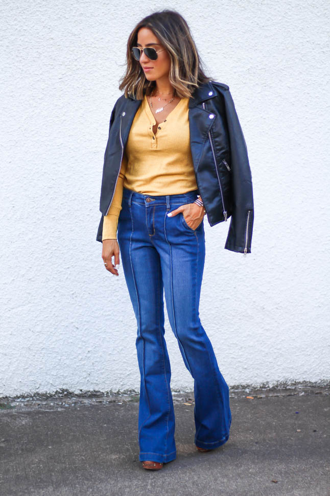 lifestlye and fashion blogger alexis belbel wearing a head to toe look from walmart we dress america. Wearing a faux leather moto jacket, yellow henley top with buttons, and high rise flare jeans for fall